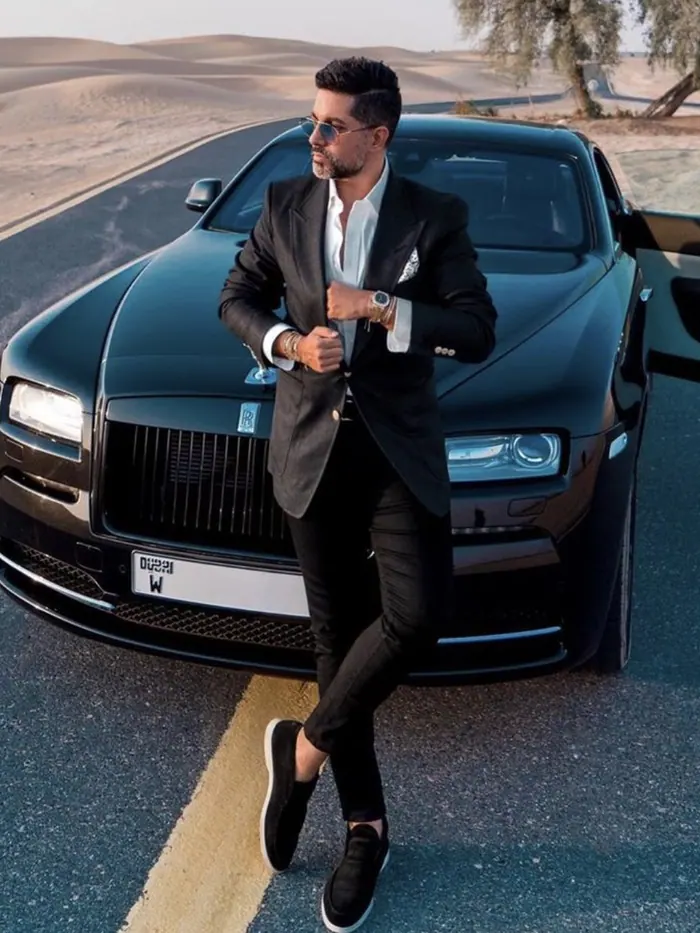 Paddock member in a black suit beside a blacked-out Rolls-Royce Wraith